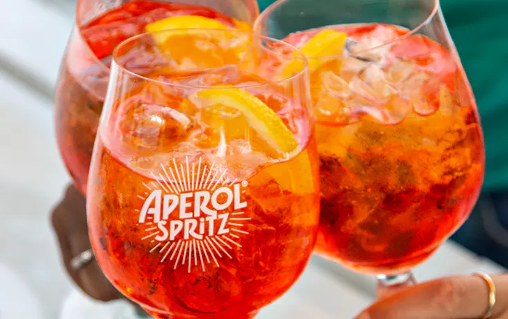 three bright orange Aperol Spritz cocktails.