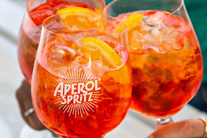 three bright orange Aperol Spritz cocktails.