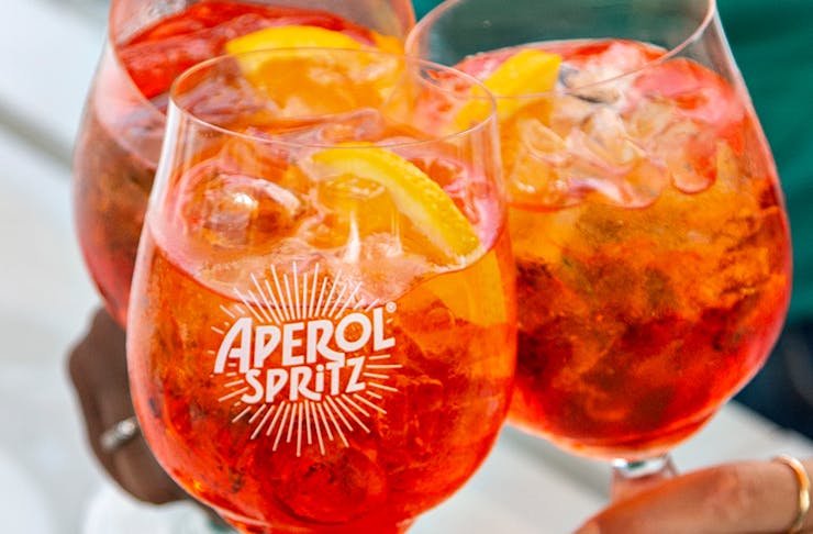 three bright orange Aperol Spritz cocktails.