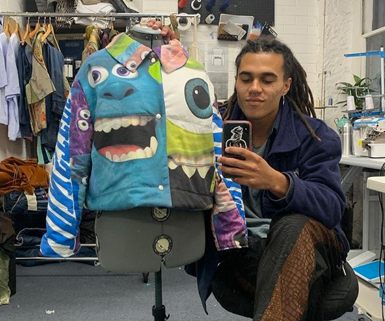 monster print on puffer jacket an dman posing with phone