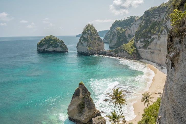 huge stone cliffs next to an isolated beach in bali