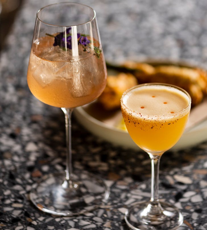 two cocktail glasses filled with floral drink