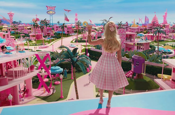a life sized barbie doll standing and overlooking barbieland
