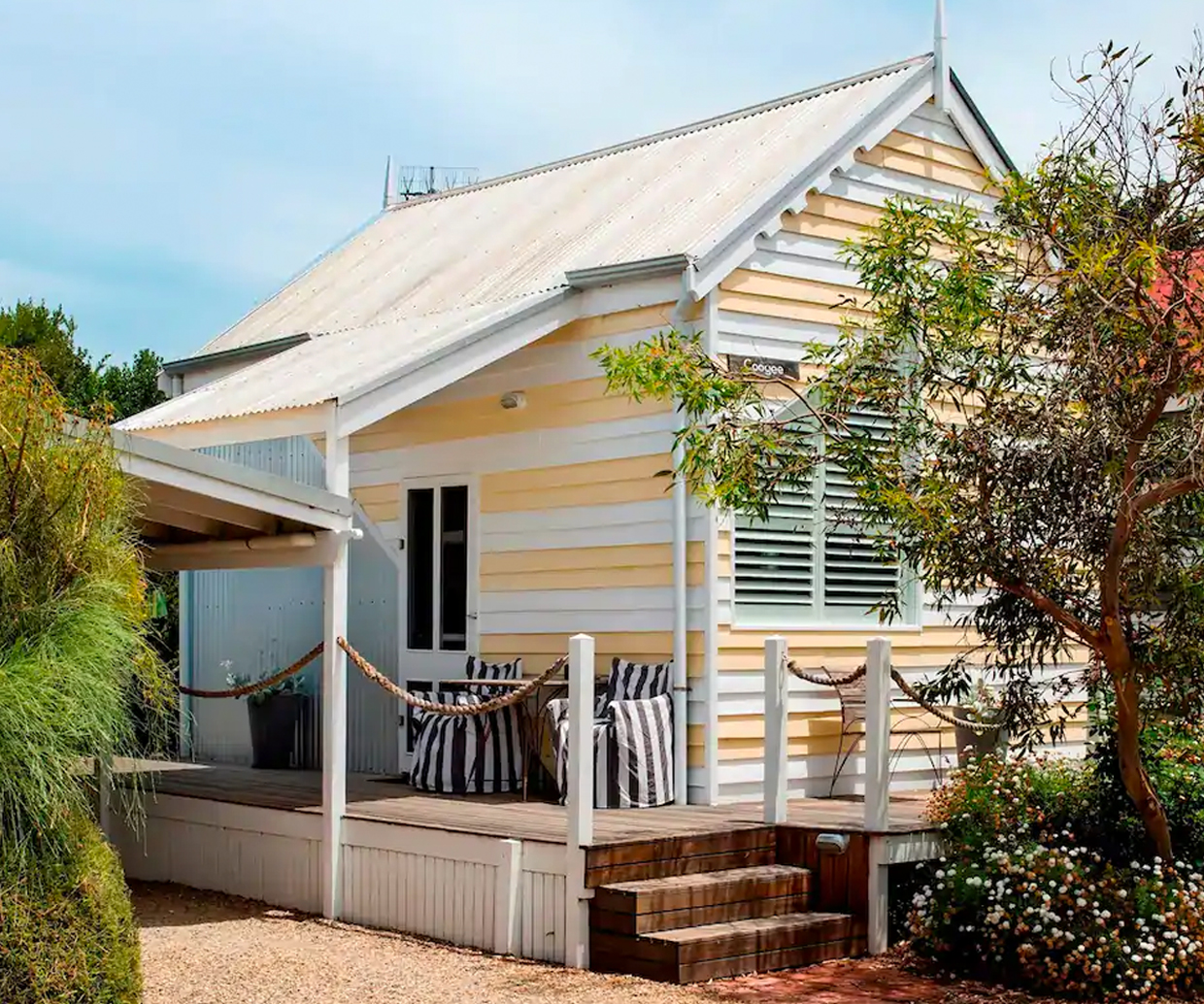 striped 70s-style beach hut surrounded by plants