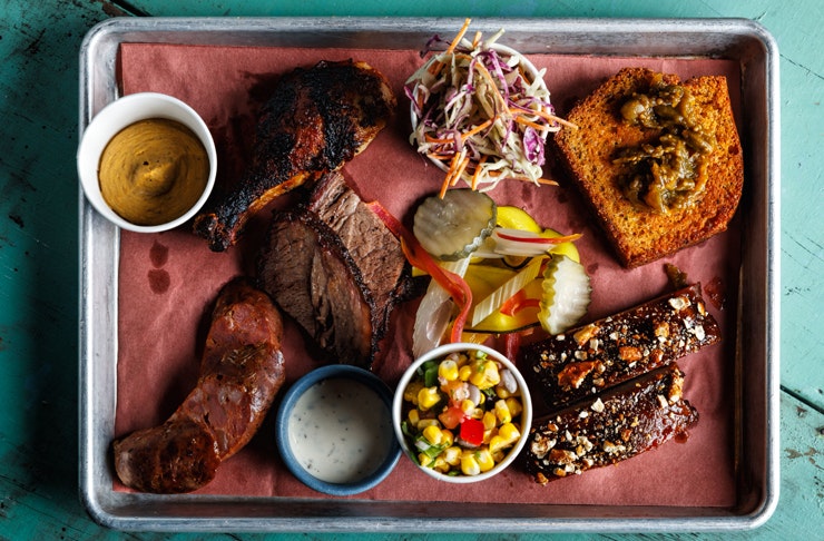 metal platter filled with juicy smoked meat, corn side, sold slaw and hickory sauce