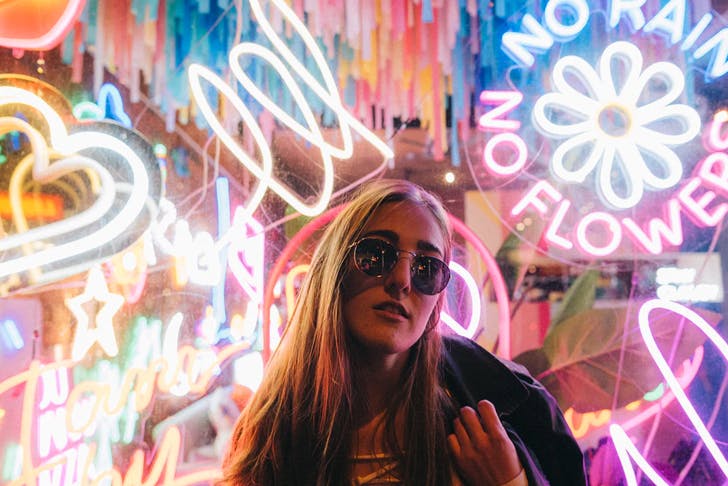 girl with long hair standing in front of neon signs
