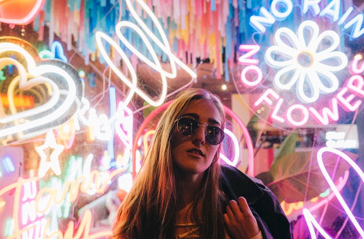 girl with long hair standing in front of neon signs