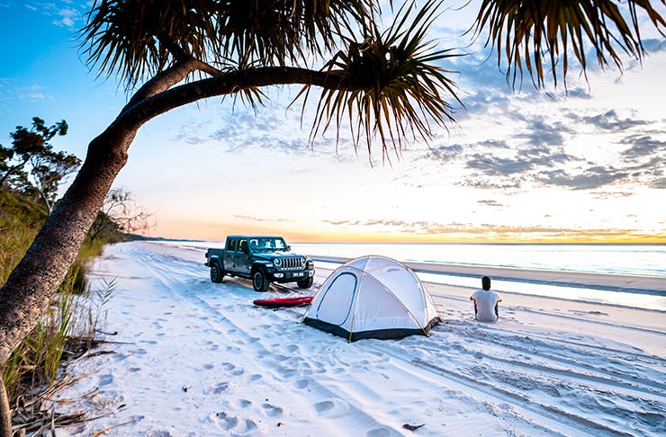 man on beach with tent and 4wd