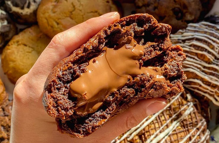 hand holding cookie over batch of cookies