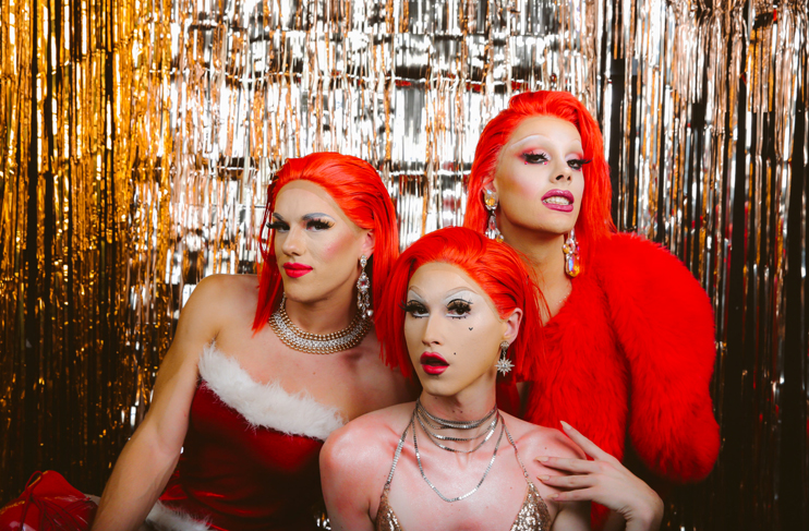 three drag queens in front of silver backdrop