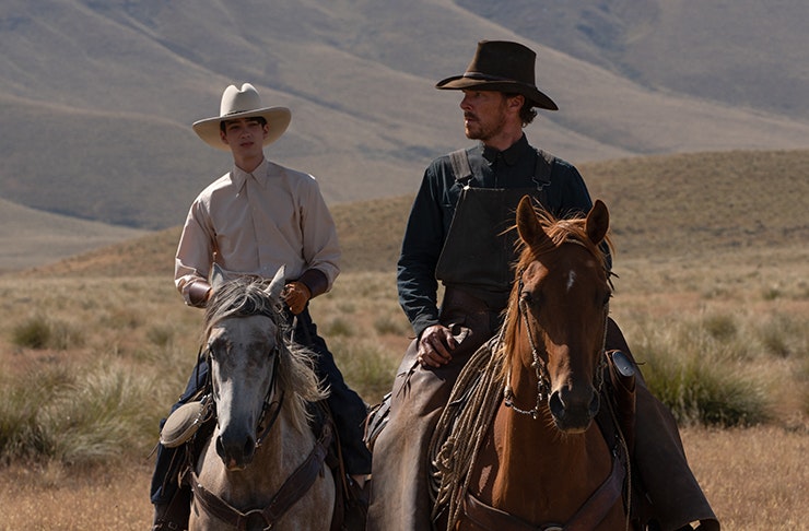 two men in cowboy hats riding horses in a valley