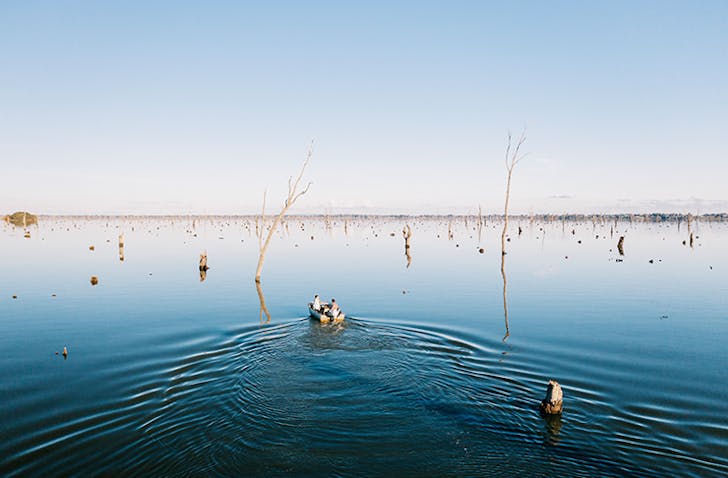 two people in tinny boating through lake