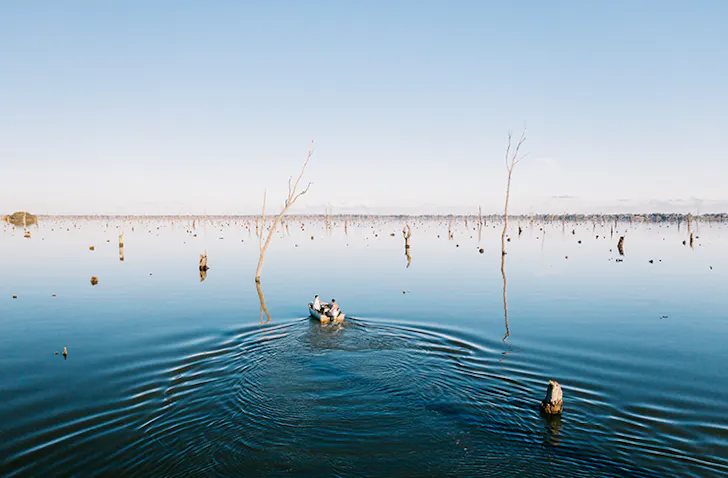 two people in tinny boating through lake