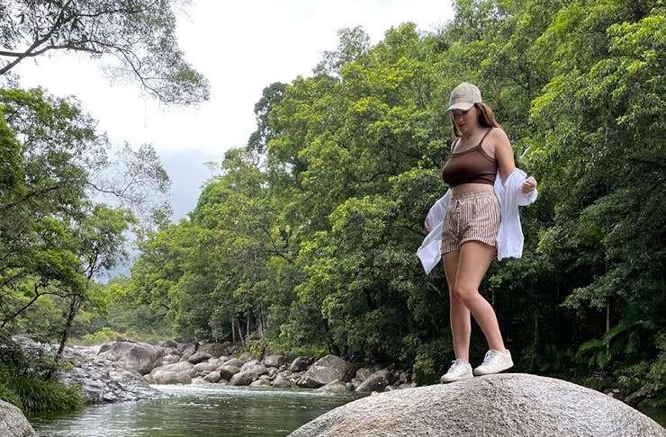 woman standing on a rock in the middle of the forest