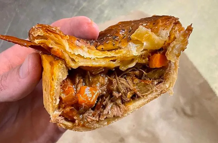 hand holding half-cut meat pie