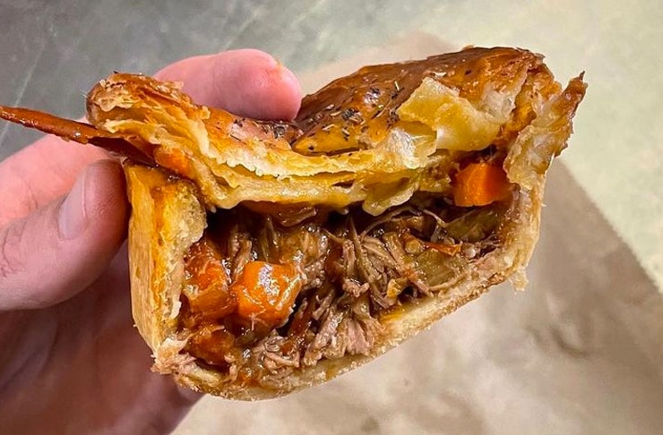 hand holding half-cut meat pie