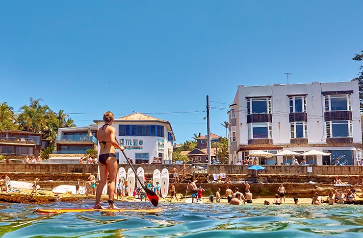people swimming and paddling in small beach enclave