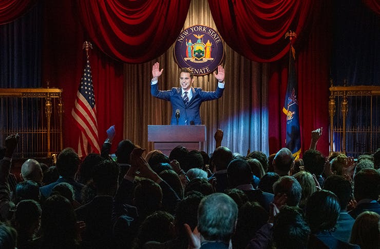 man standing at podium addressing room of people