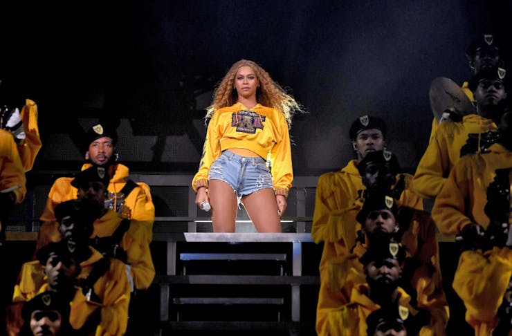beyonce stands in the middle of the stage at coachella with her troop of dancers.