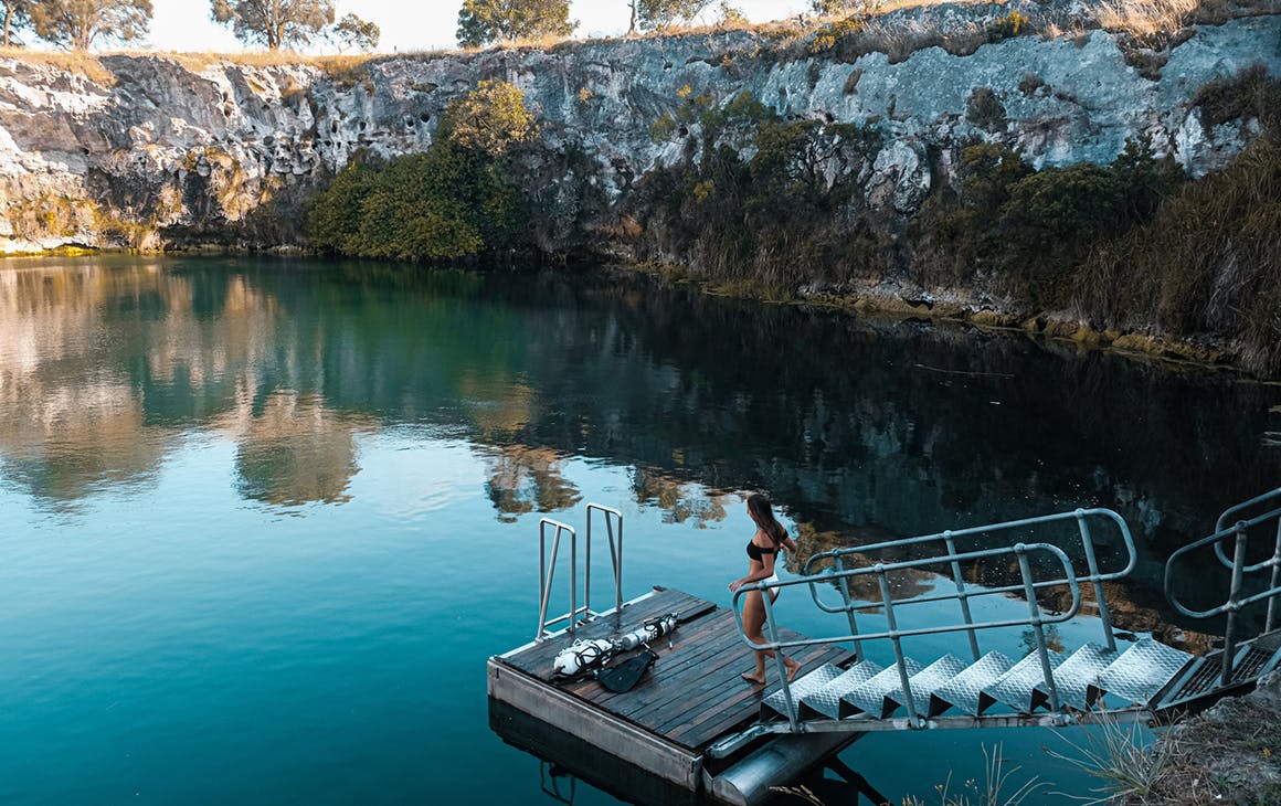 a woman walks on a pontoon at Little Blue Lake