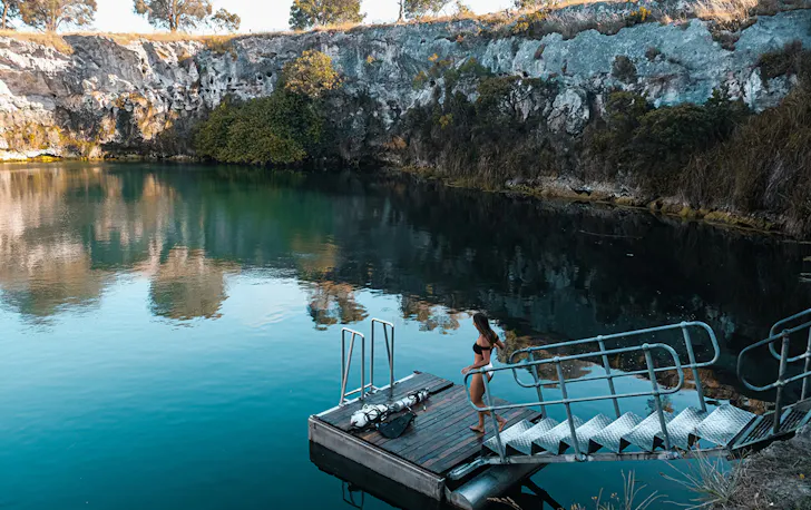 a woman walks on a pontoon at Little Blue Lake