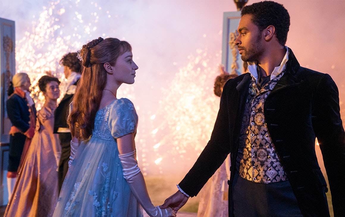 a young man and a woman meet in the middle of the dance floor, fireworks behind them.