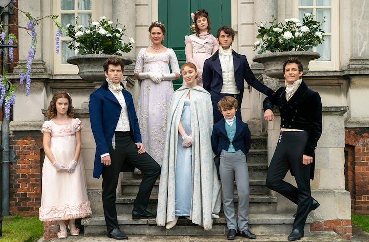 The cast of the Bridgerton family pose on steps outside a stately house