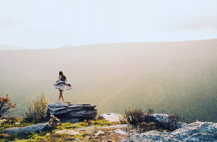 young woman walking along rocky cliff