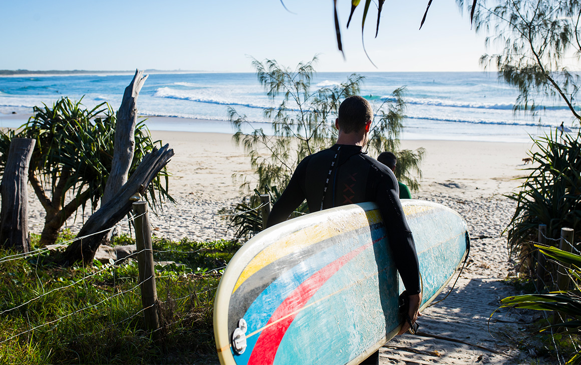 a man holding a surf board walks into the ocean