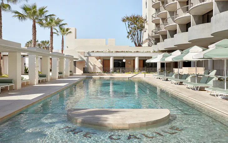 A stunning crystal clear pool surrounded by cream sun lounges and cabanas