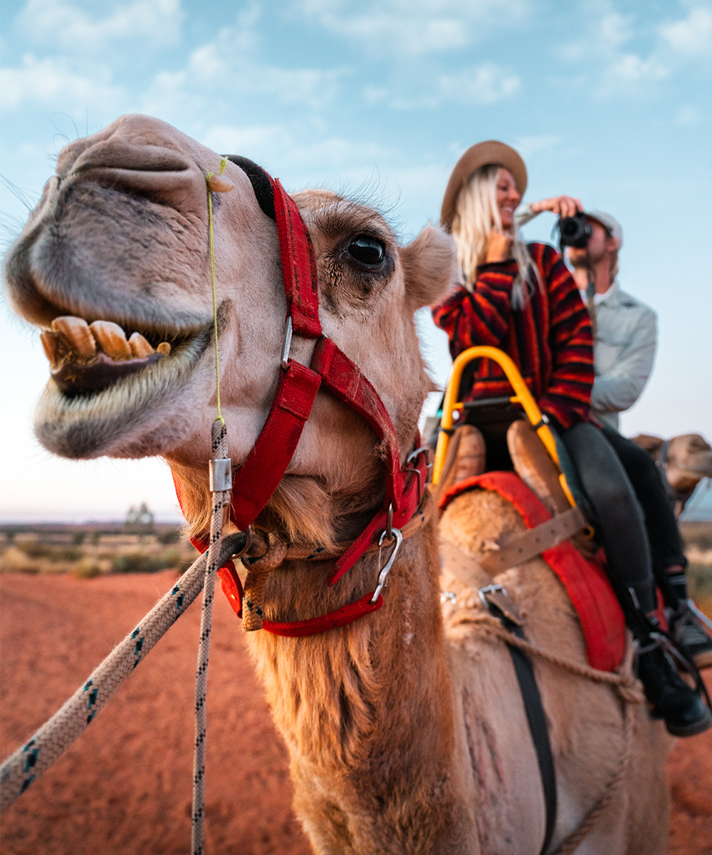 a man and woman ride a camel in the desert.