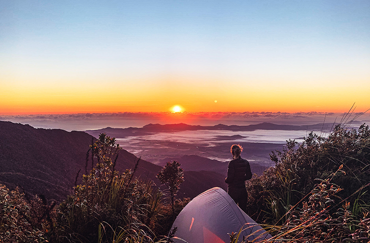 person camping on top of mountain at sunrise
