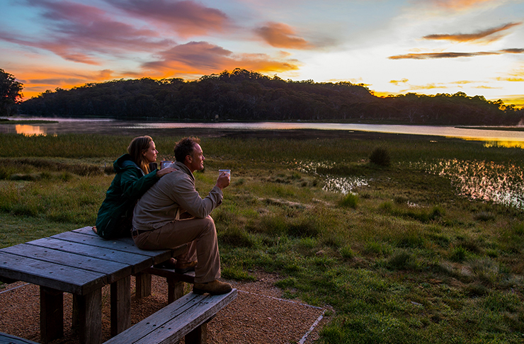 deux personnes assises sur un banc en regardant le soleil se coucher