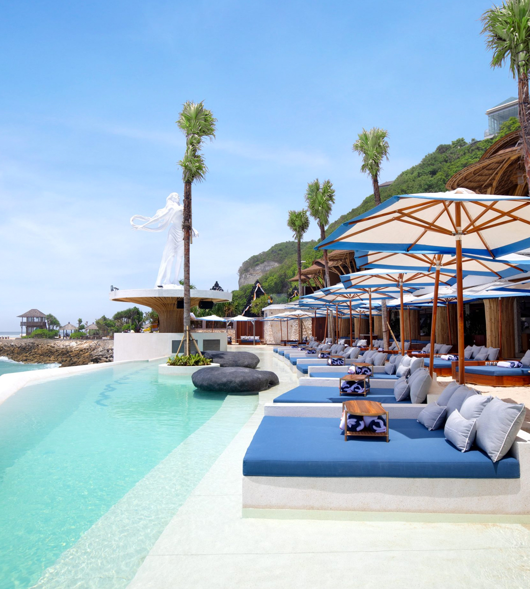 an infinity pool overlooking the beach with cabanas