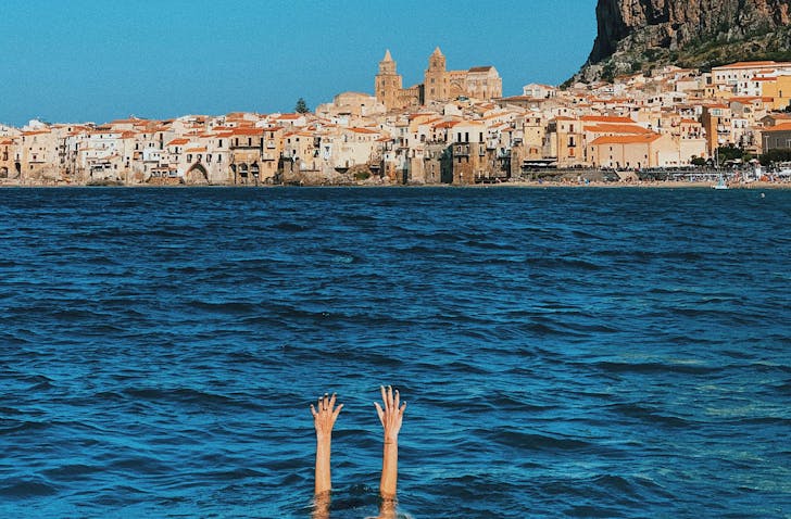 a person submerged underwater with their hands out of the ocean