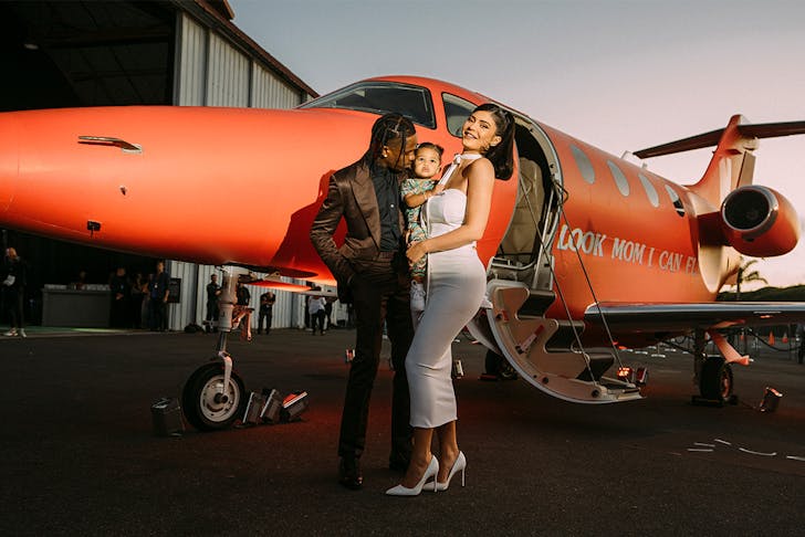 Travis Scott with his wife and child outside a plane.
