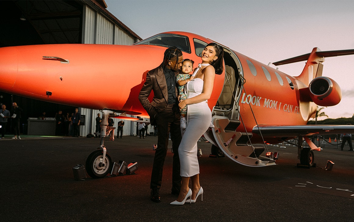 Travis Scott with his wife and child outside a plane.