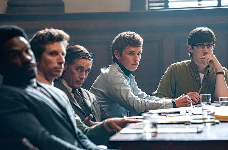 a group of young men sit behind a desk in a courtroom