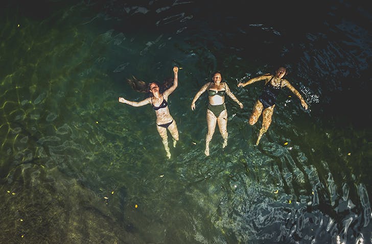 three girls floating on their backs in swimming hole