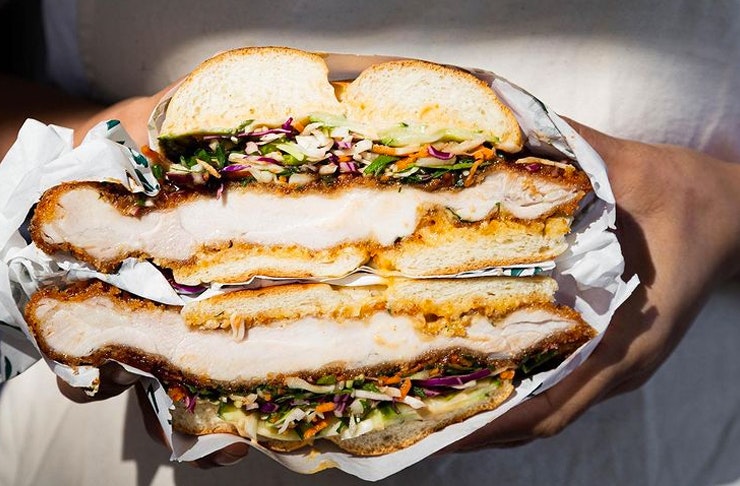 hands holding chicken katsu bagel burger