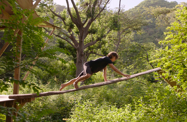 man climbing suspended log in costa rica jungle