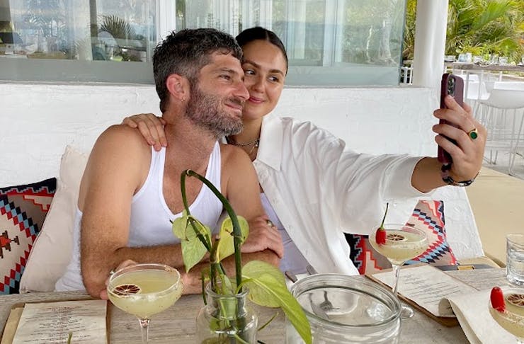 two people sitting at a cafe table taking a selfie