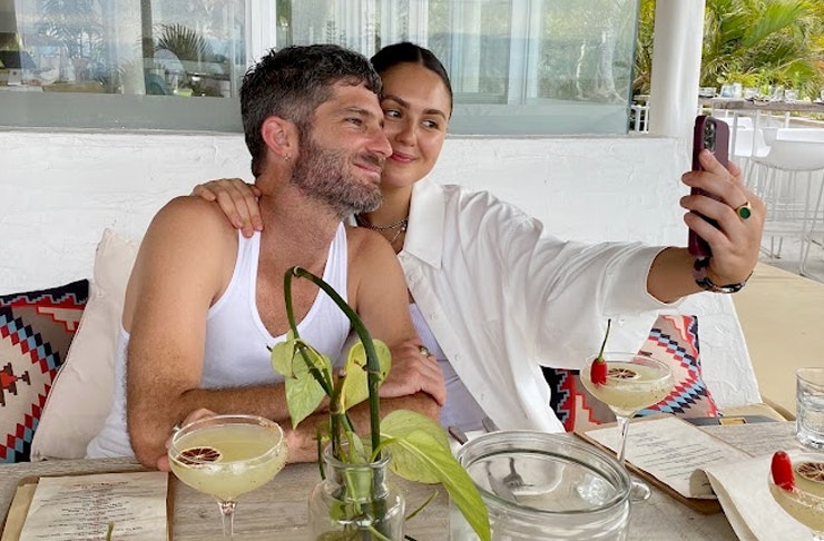 two people sitting at a cafe table taking a selfie
