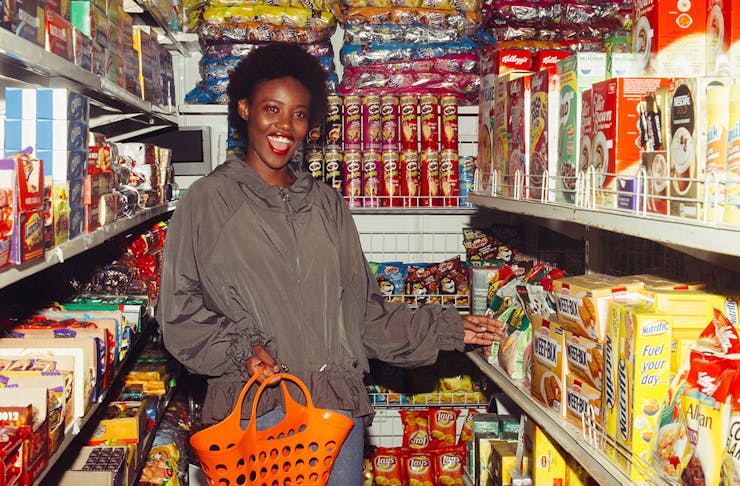 a woman shops in a grocery store, full of colourful aisles. 