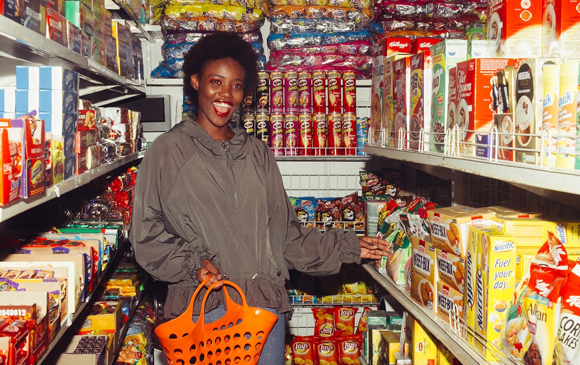 a woman shops in a grocery store, full of colourful aisles. 