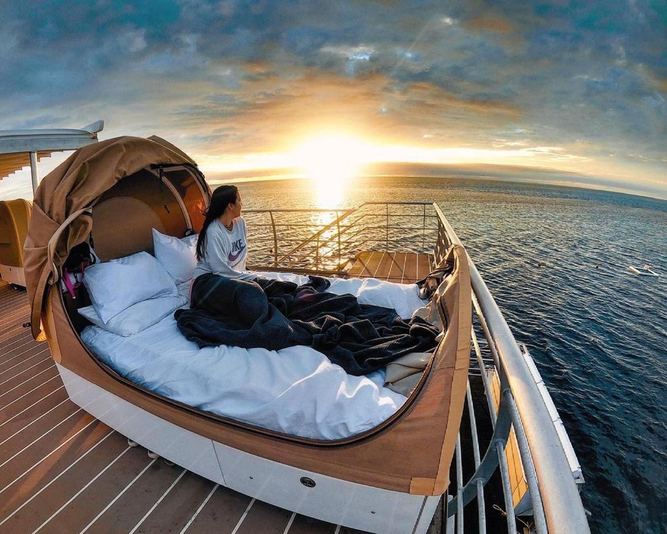 A custom made bed on the deck of a ship looking over the ocean