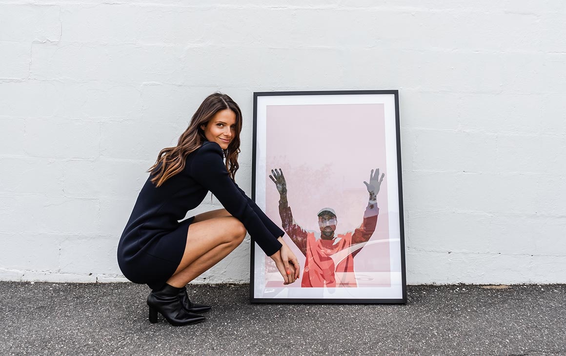 Artist Dom Gauci crouches down next to a framed piece of her art work