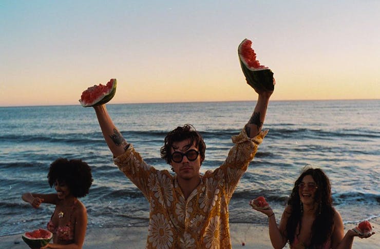 harry styles holding watermelons on the beach at sunset