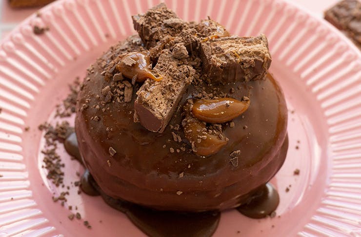 A close-up of Doughnut Time's Life On Mars doughnut, covered in a chocolate glaze and topped with pieces of a Mars bar.