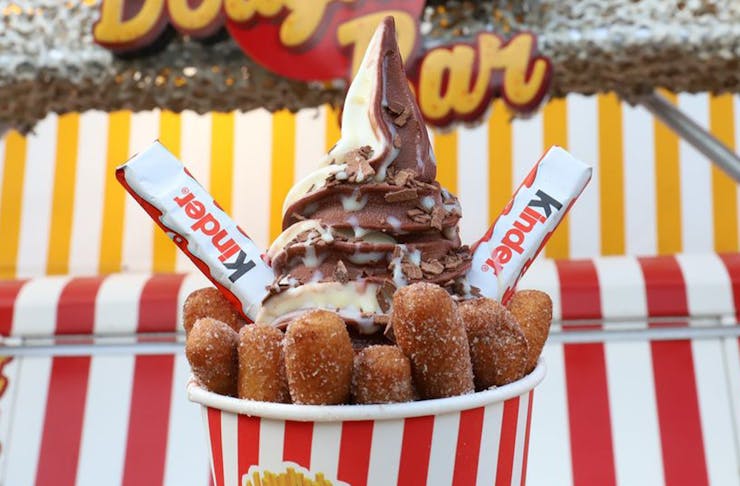 doughnut fries topped with chocolate and vanilla soft serve swirl topped with two kinder bars 